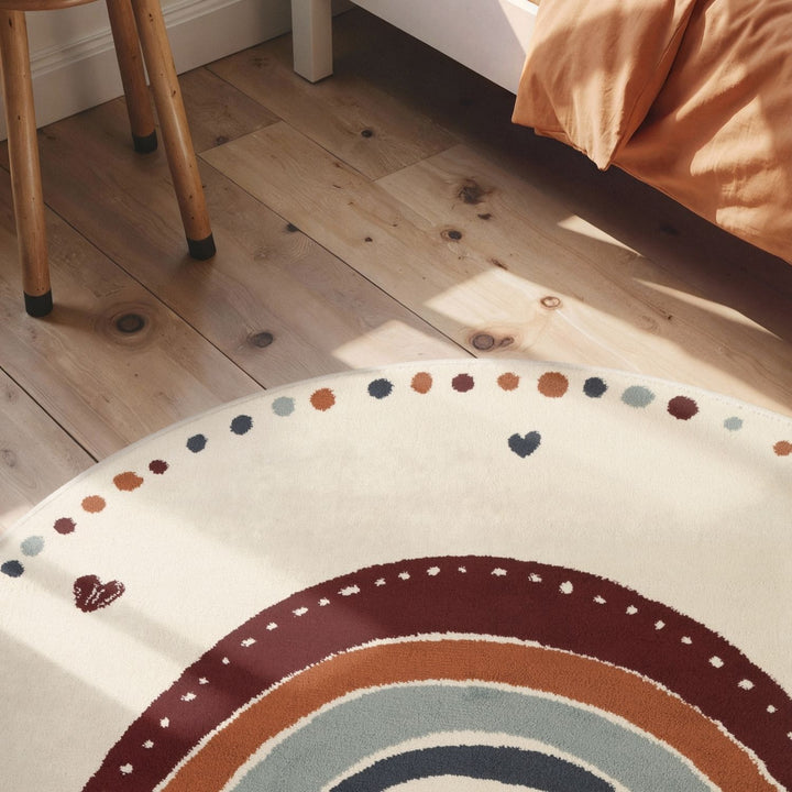 Round rug with a rainbow design on a wooden floor.