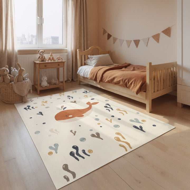Children's room with a whale-patterned rug, wooden bed, and toys.