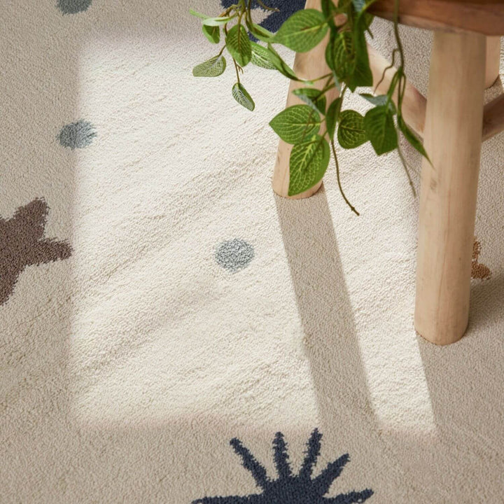 Close-up of a textured rug with abstract patterns and a plant on a wooden surface.