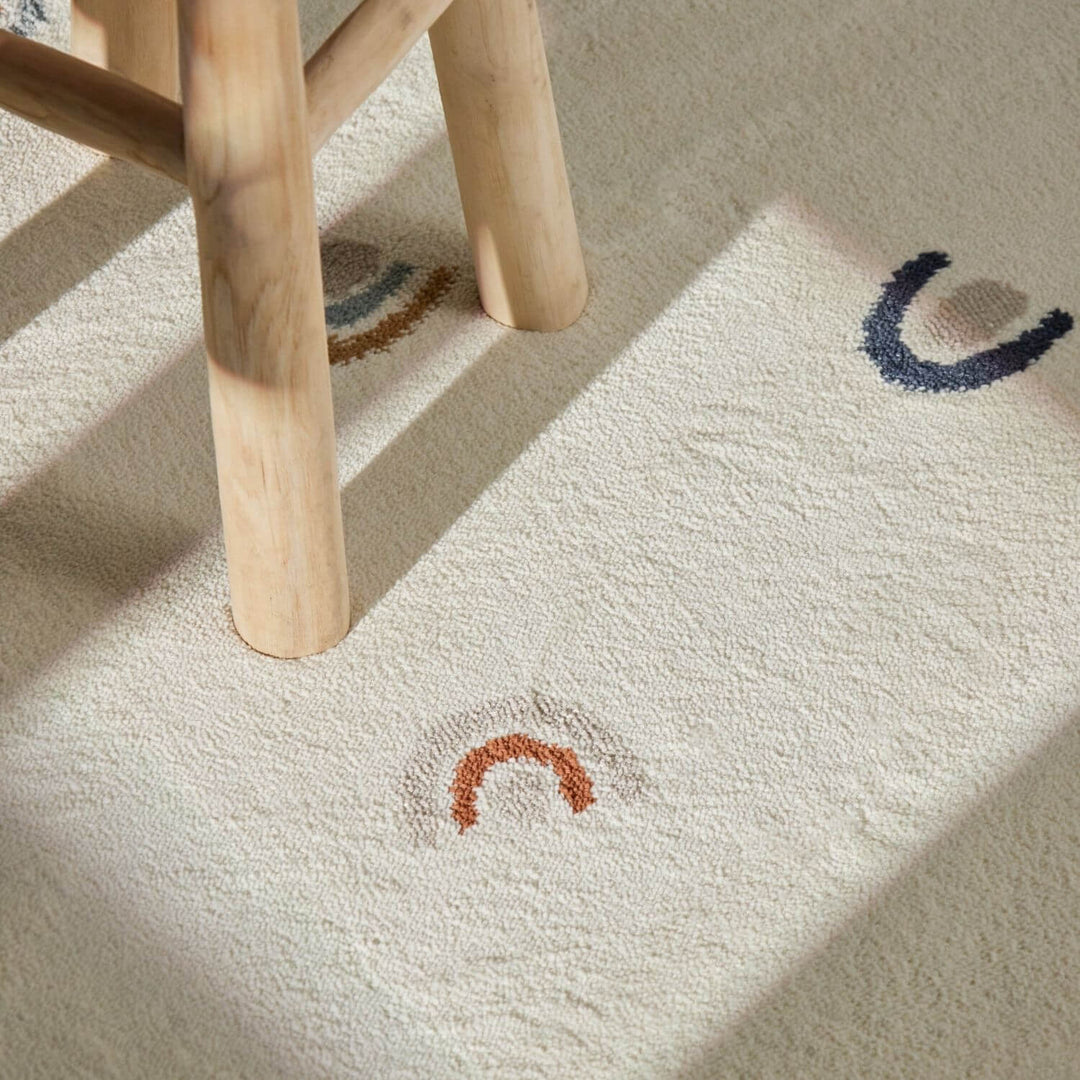 Close-up of a textured rug with embroidered designs and wooden legs.