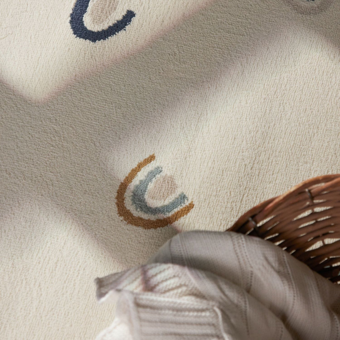 Close-up of a textured fabric with embroidered design and a hand holding a woven basket.