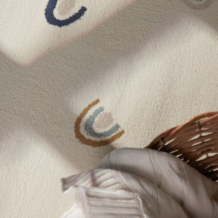 Close-up of a textured fabric with embroidered design and a hand holding a woven basket.