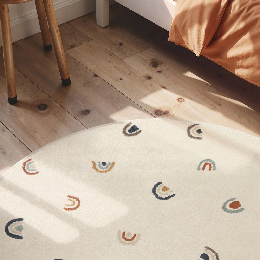 Round white rug with rainbow pattern on a wooden floor