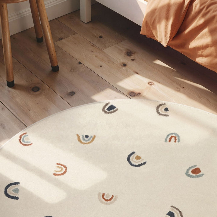 Round white rug with rainbow pattern on a wooden floor