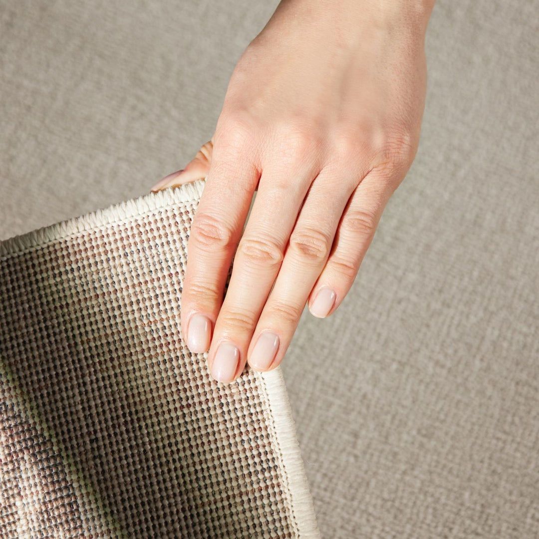 Hand holding a textured fabric against a neutral background