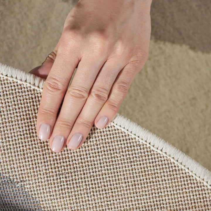 Hand touching a textured beige fabric surface