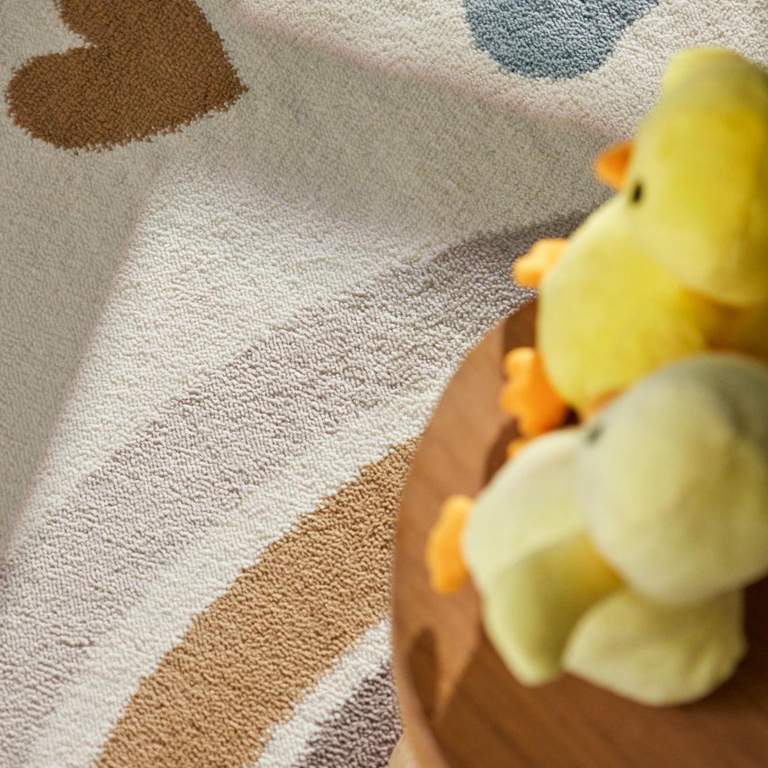 Yellow plush duck toy on a wooden block with a patterned carpet background