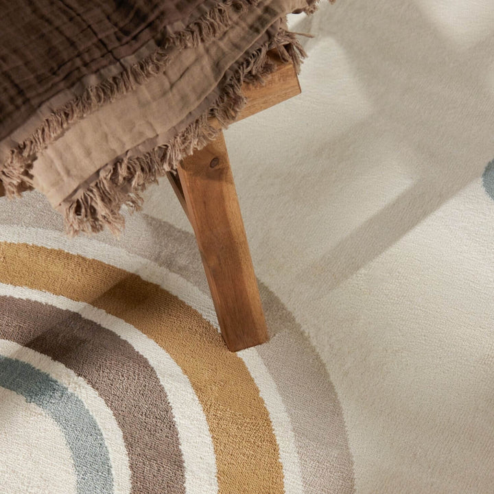 Close-up of a wooden stool with a textured brown fabric on a patterned rug.