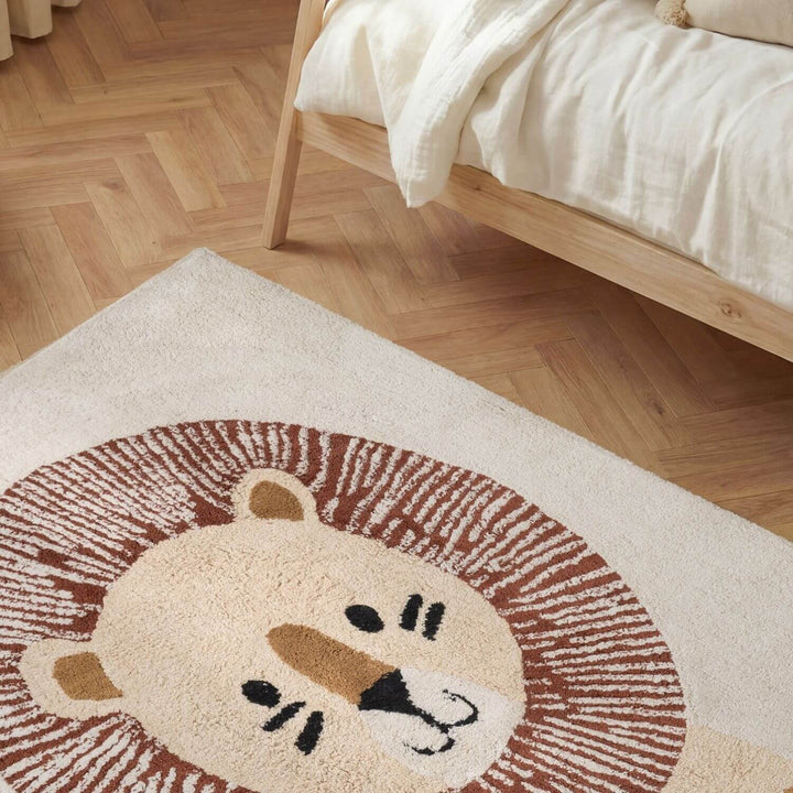 Lion-themed rug on a wooden floor with a bed in the background