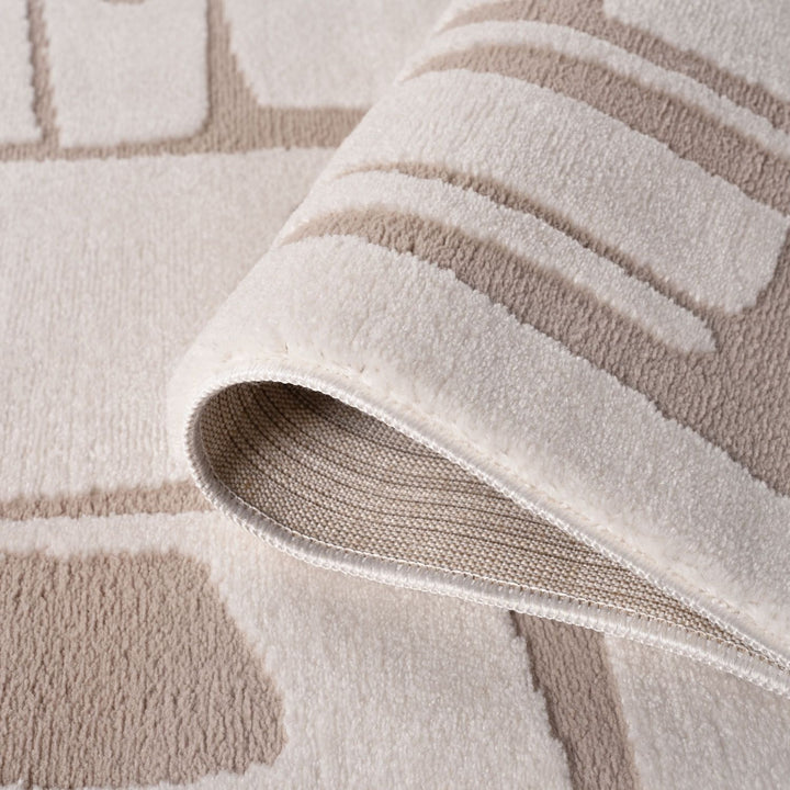 Close-up of a textured beige and white rug with geometric patterns.