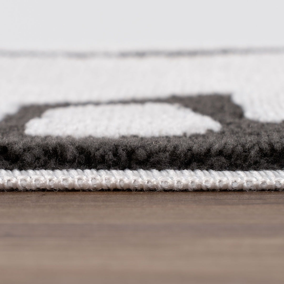 Close-up of a textured rug with geometric pattern on a wooden floor.