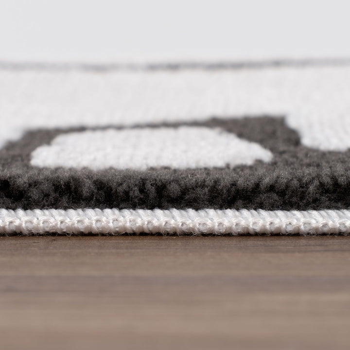 Close-up of a textured rug with geometric pattern on a wooden floor.