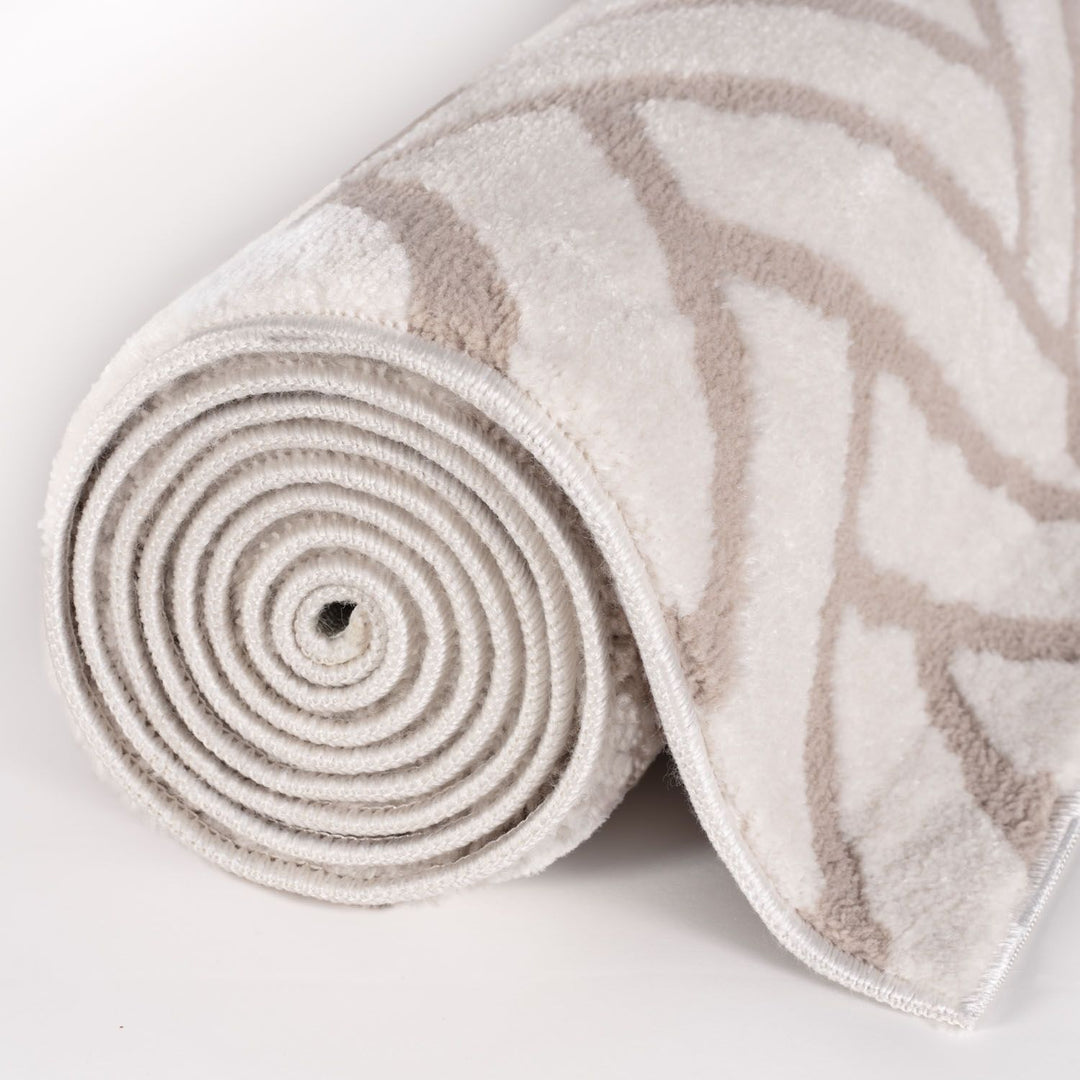 Rolled-up beige and brown patterned rug on a light gray background