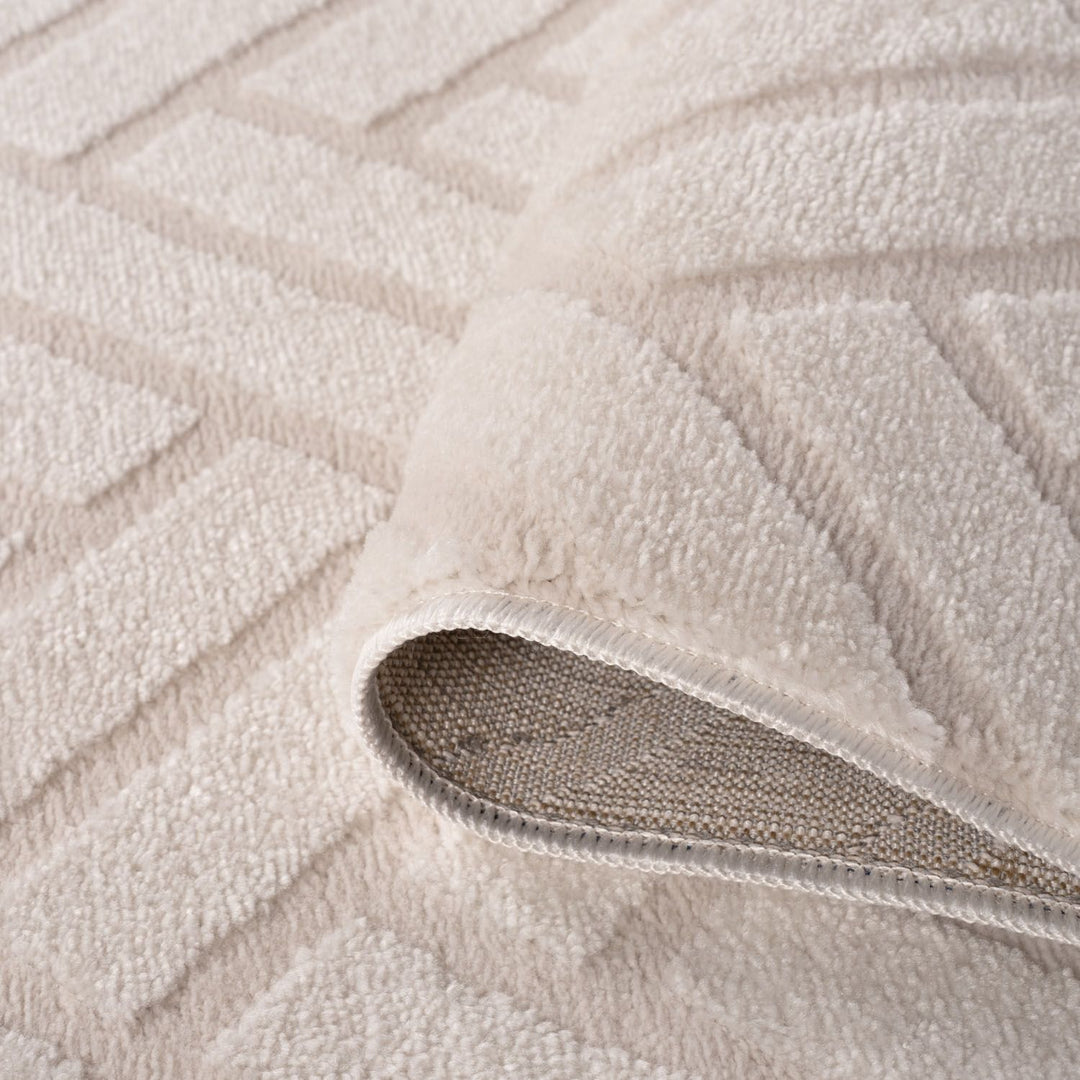 Close-up of a textured beige rug with a focus on the fabric and pattern.
