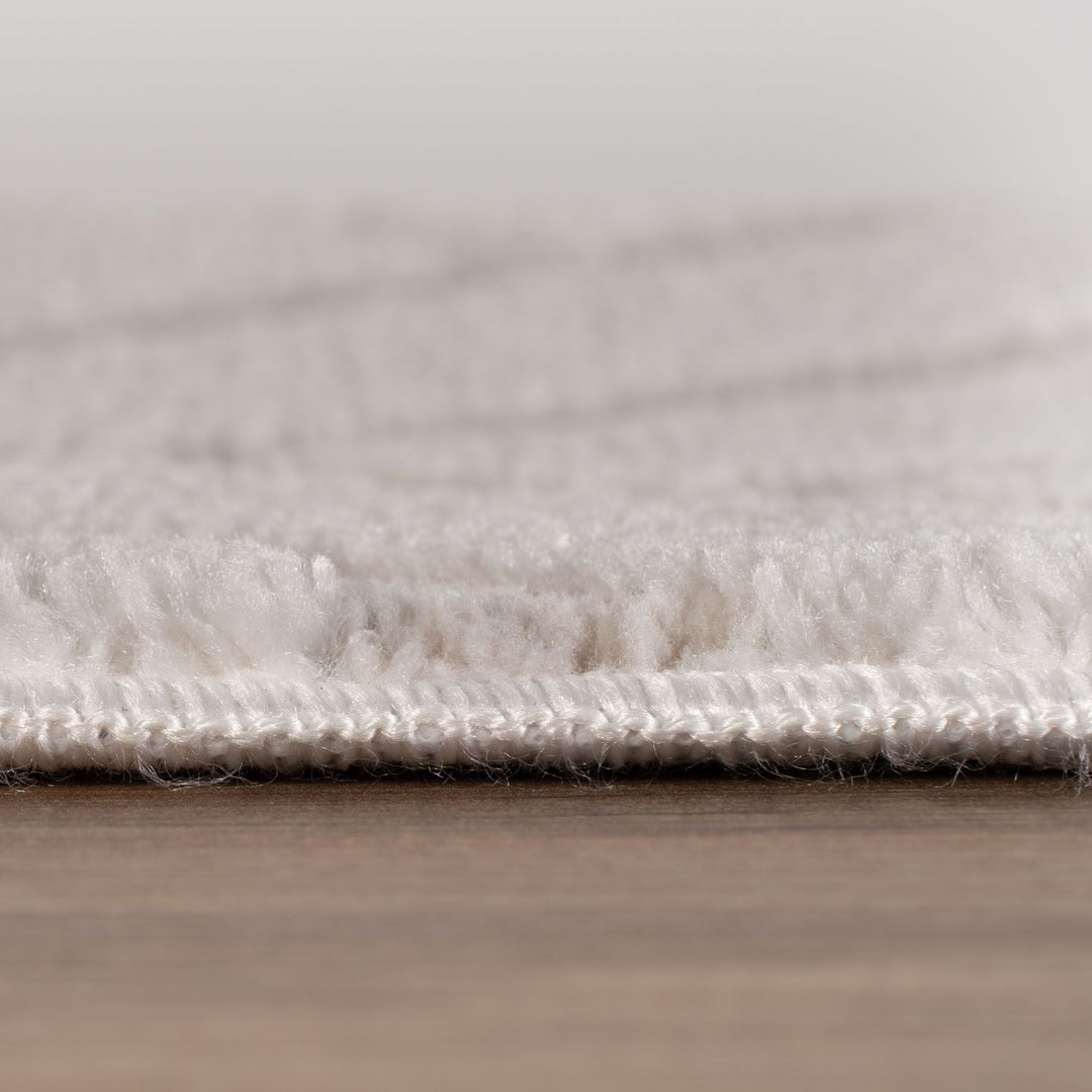 Close-up of a textured white rug on a wooden floor