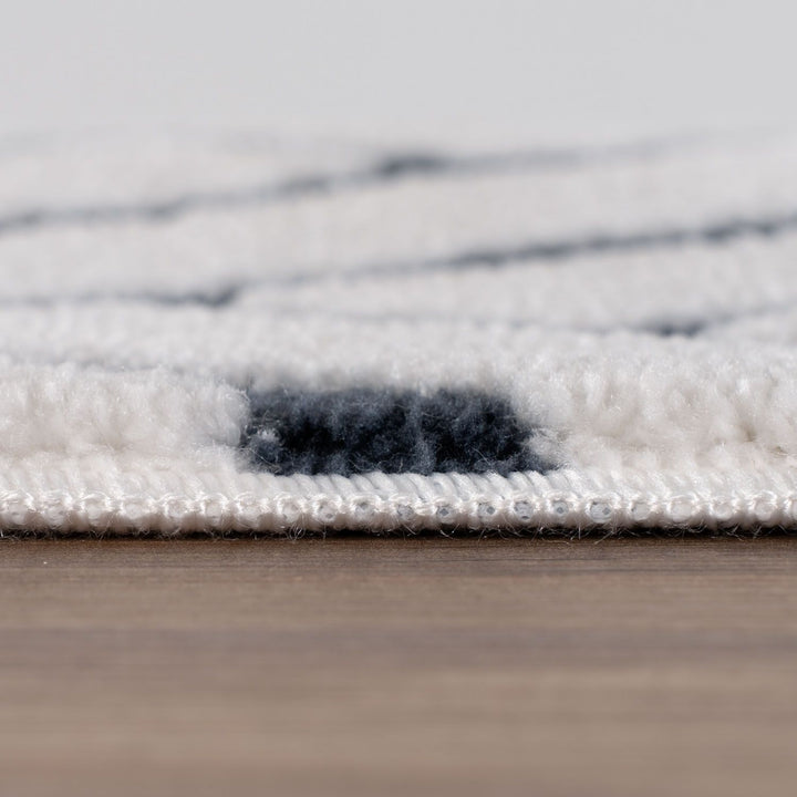 Close-up of a textured rug with a neutral color palette on a wooden floor.