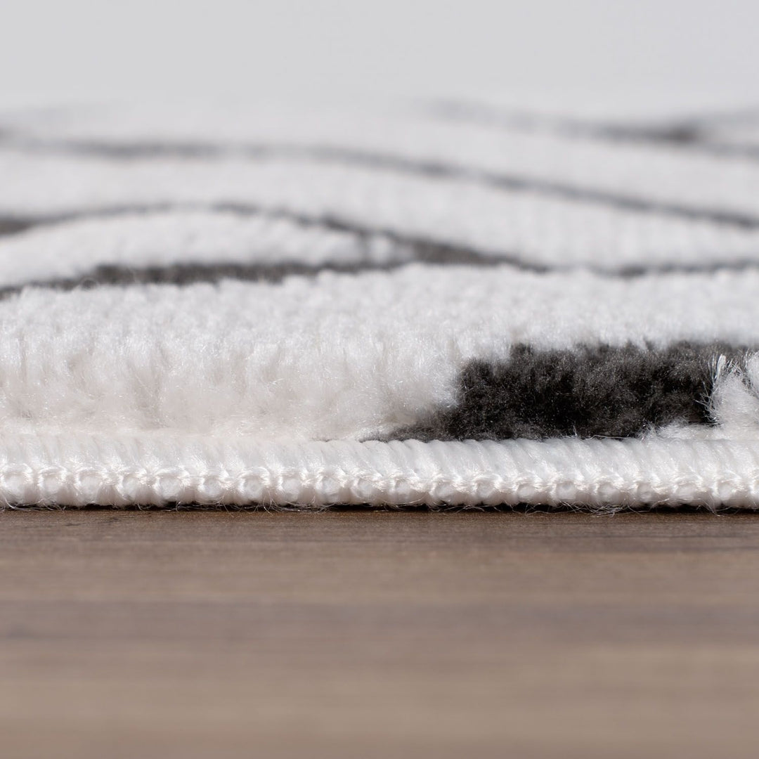 Close-up of a textured rug with white and gray pattern on a wooden floor.