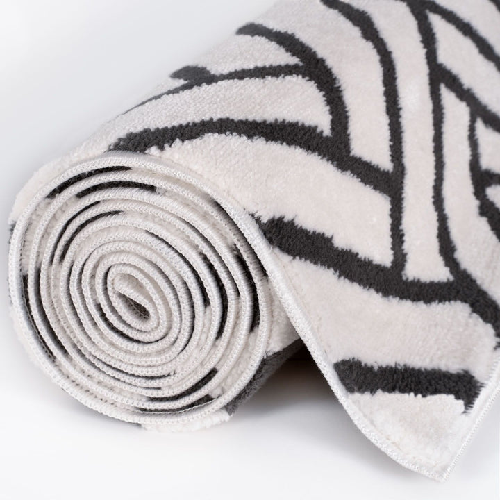 Rolled-up rug with black geometric pattern on a white background