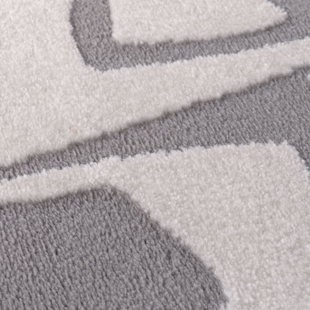 Close-up of a textured gray and white rug with geometric patterns.