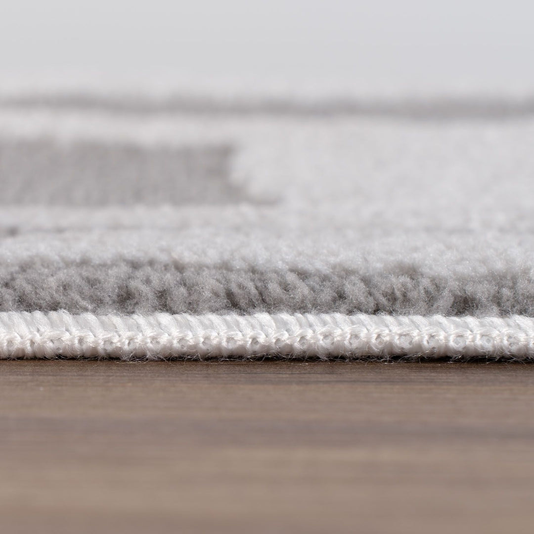 Close-up of a gray rug with a textured surface on a wooden floor.