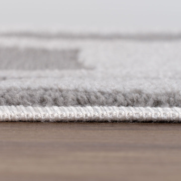 Close-up of a gray rug with a textured surface on a wooden floor.