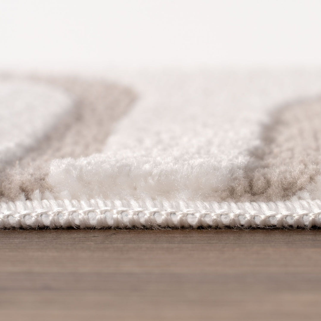 Close-up of a textured rug with a neutral color palette on a wooden floor.