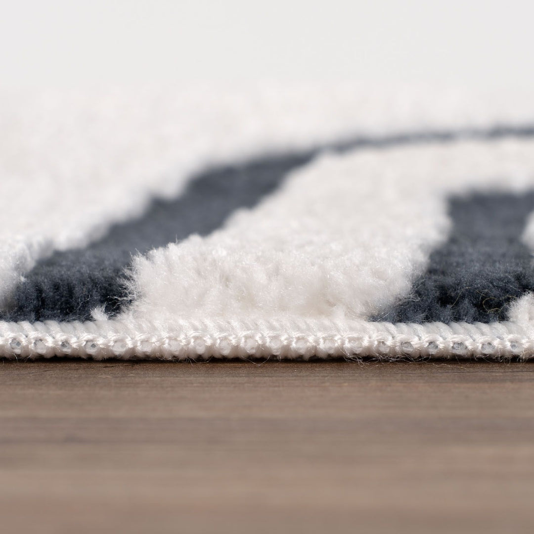 Close-up of a textured rug with a geometric pattern on a wooden floor.