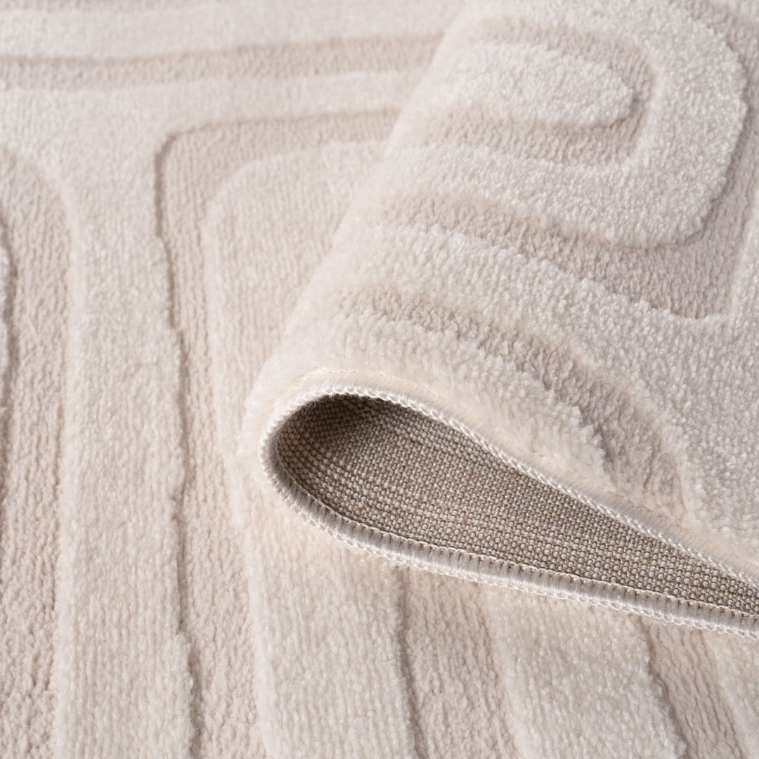 Close-up of a textured beige bath mat with a folded corner.