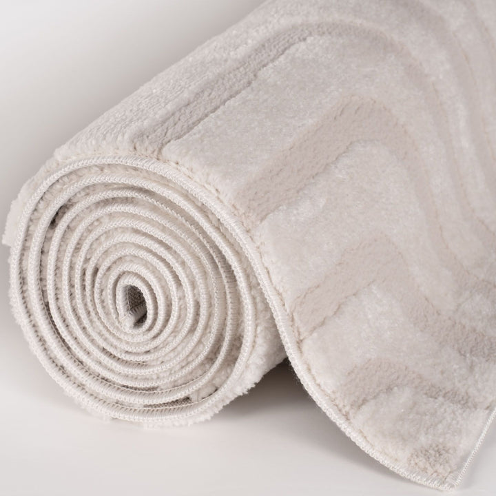 Rolled-up beige bath mat on a light gray background