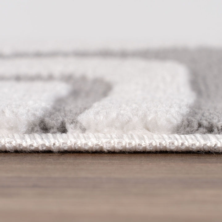 Close-up of a textured rug with a neutral color palette on a wooden floor.