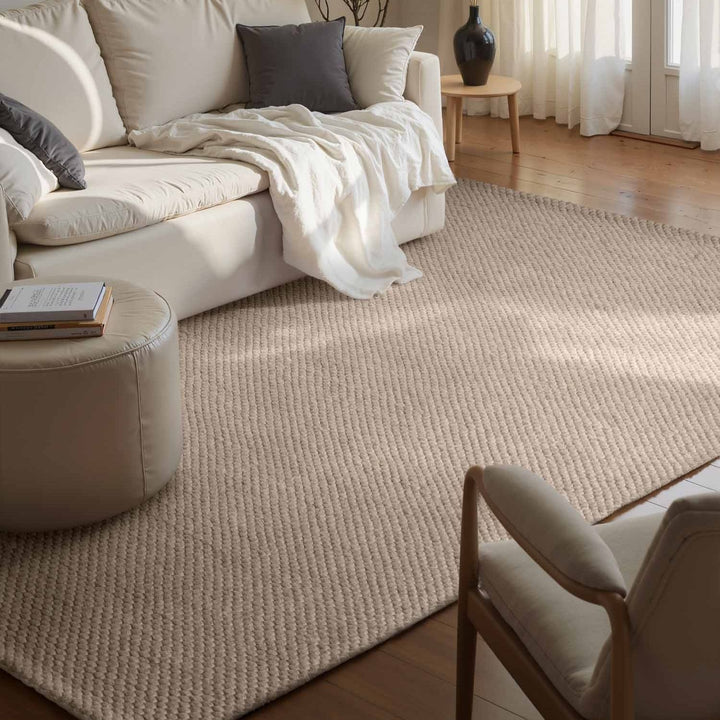 Living room with a beige rug, white sofa, and wooden coffee table.