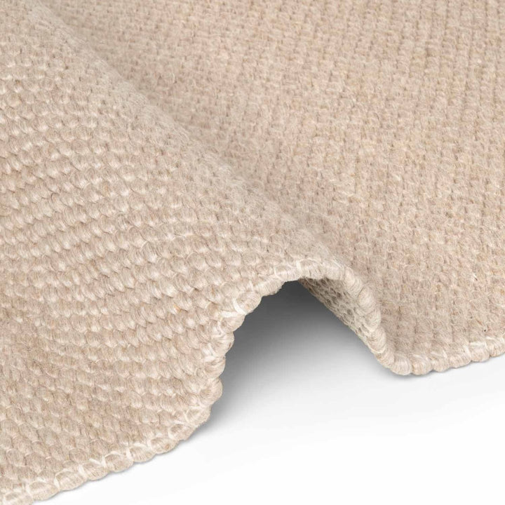 Close-up of a beige textured rug corner on a white background