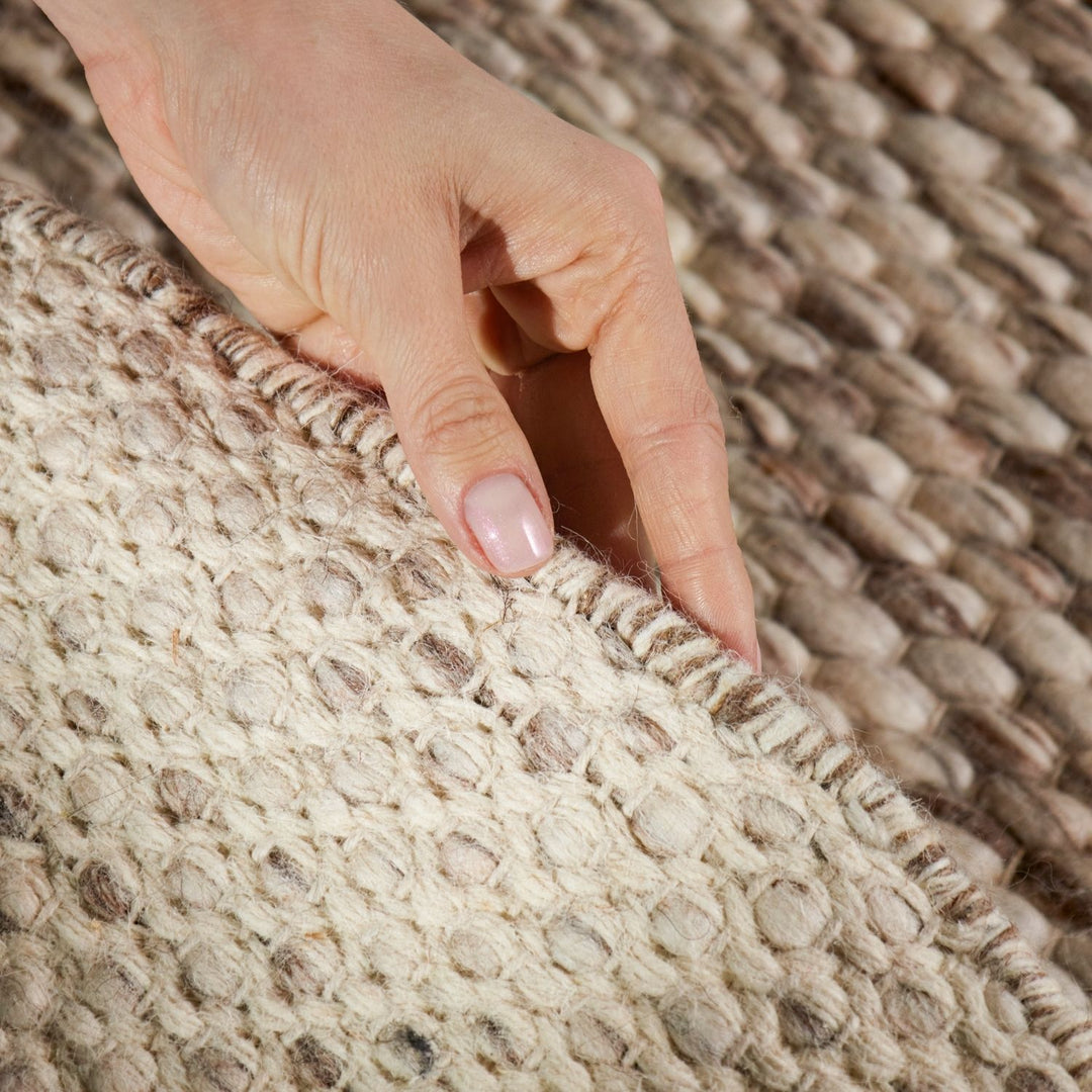 Hand touching a textured beige rug