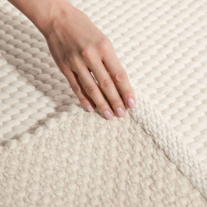 Hand touching a textured beige fabric surface