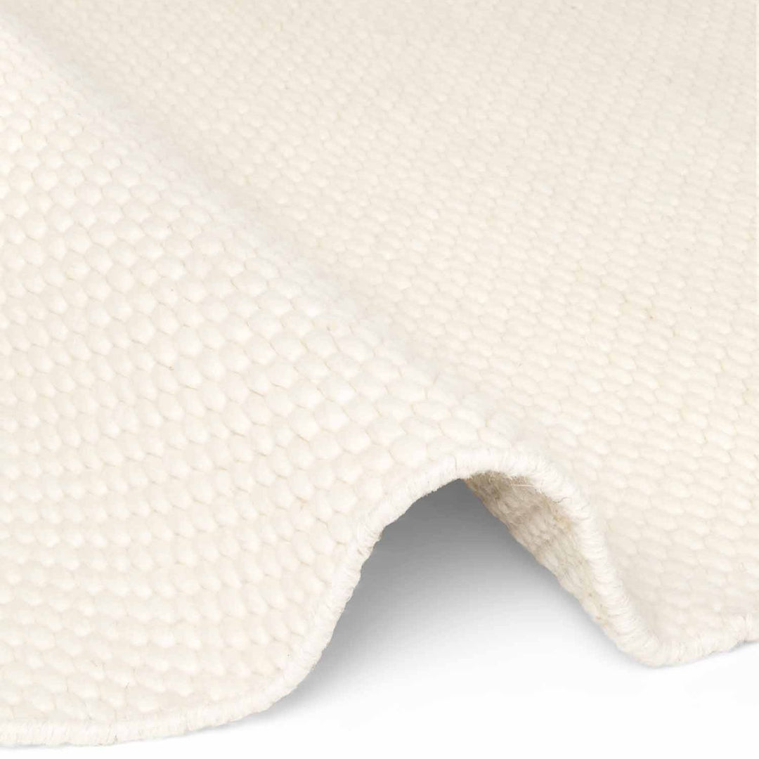 Close-up of a textured white fabric with a slight wave pattern on a white background