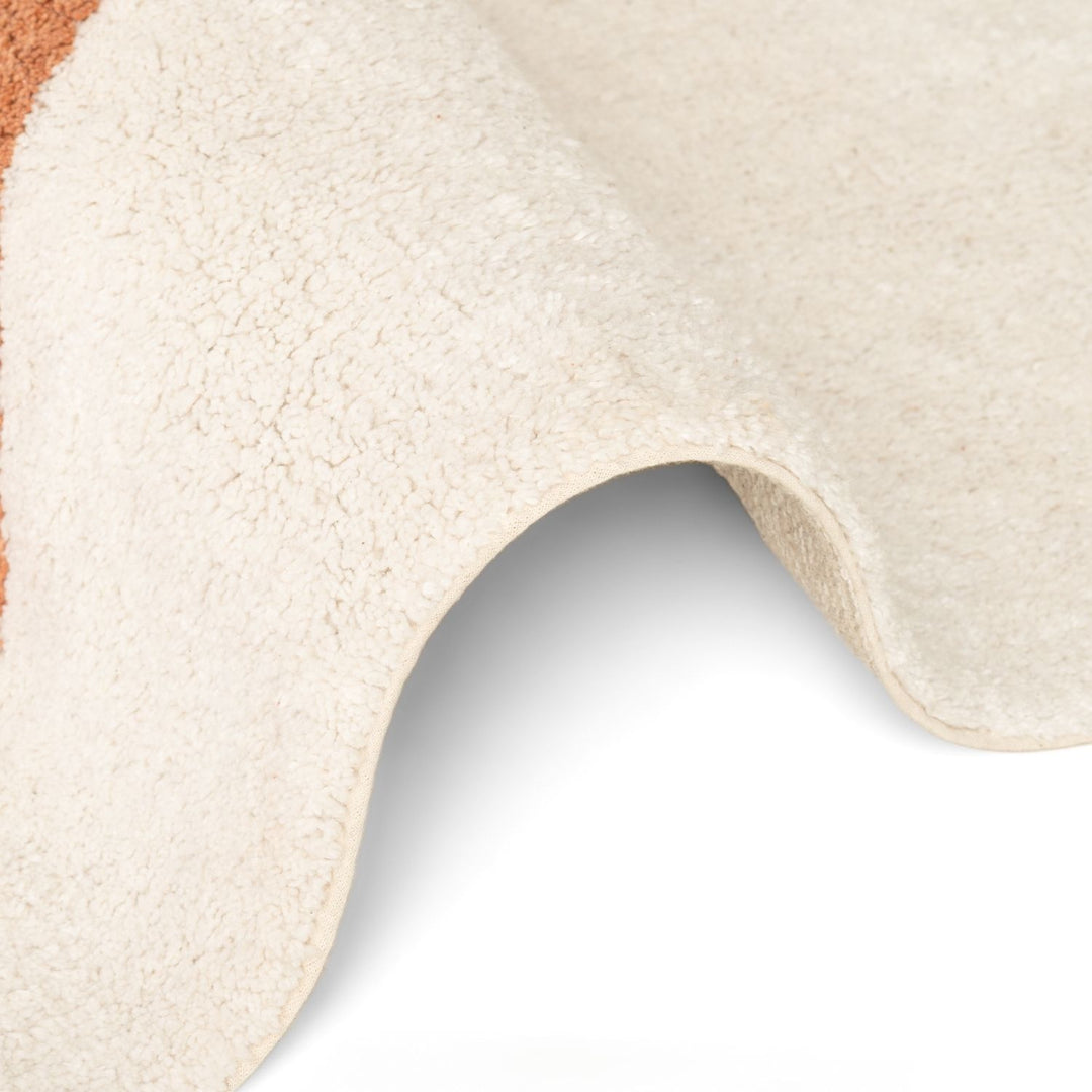 Close-up of a textured beige rug corner on a light gray background