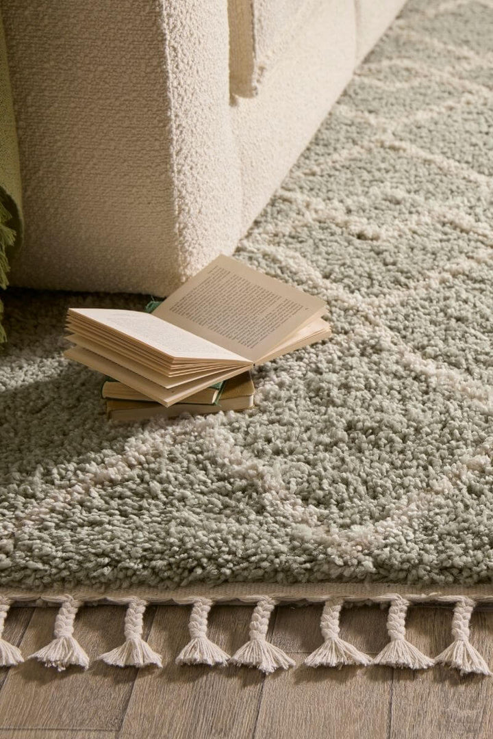 Moroccan-style rug in Eucalyptus Green with intricate design, paired with an open book on the floor.