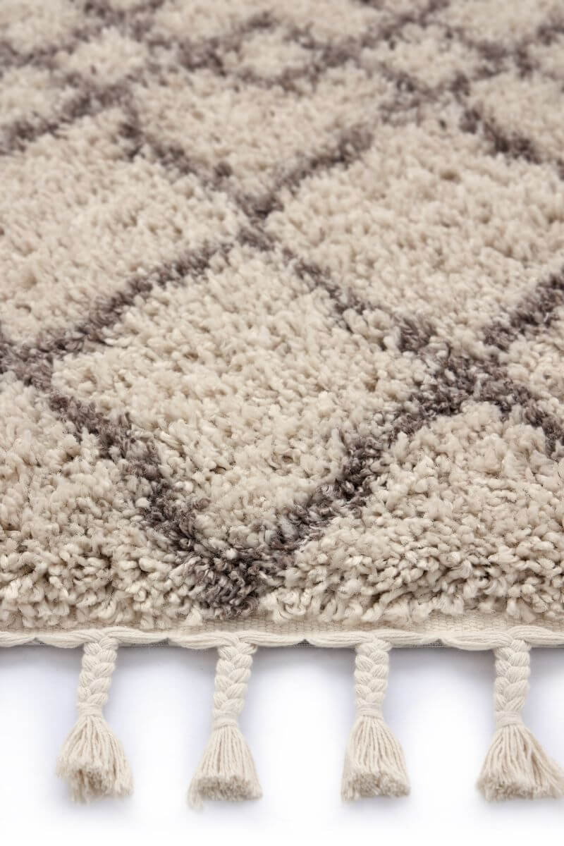 Close-up of a Moroccan-style rug in beige with intricate diamond pattern and tassels.