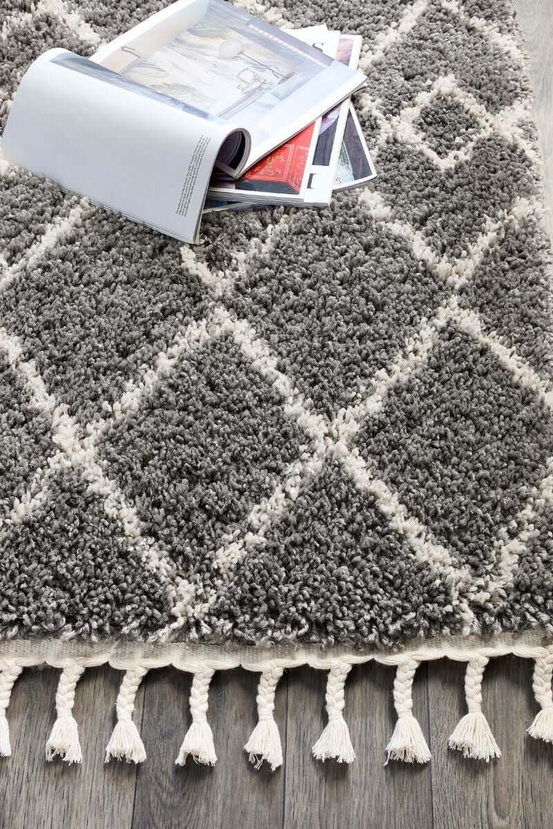 Moroccan style rug in grey with white geometric pattern and tassels, perfect for adding charm to home decor.