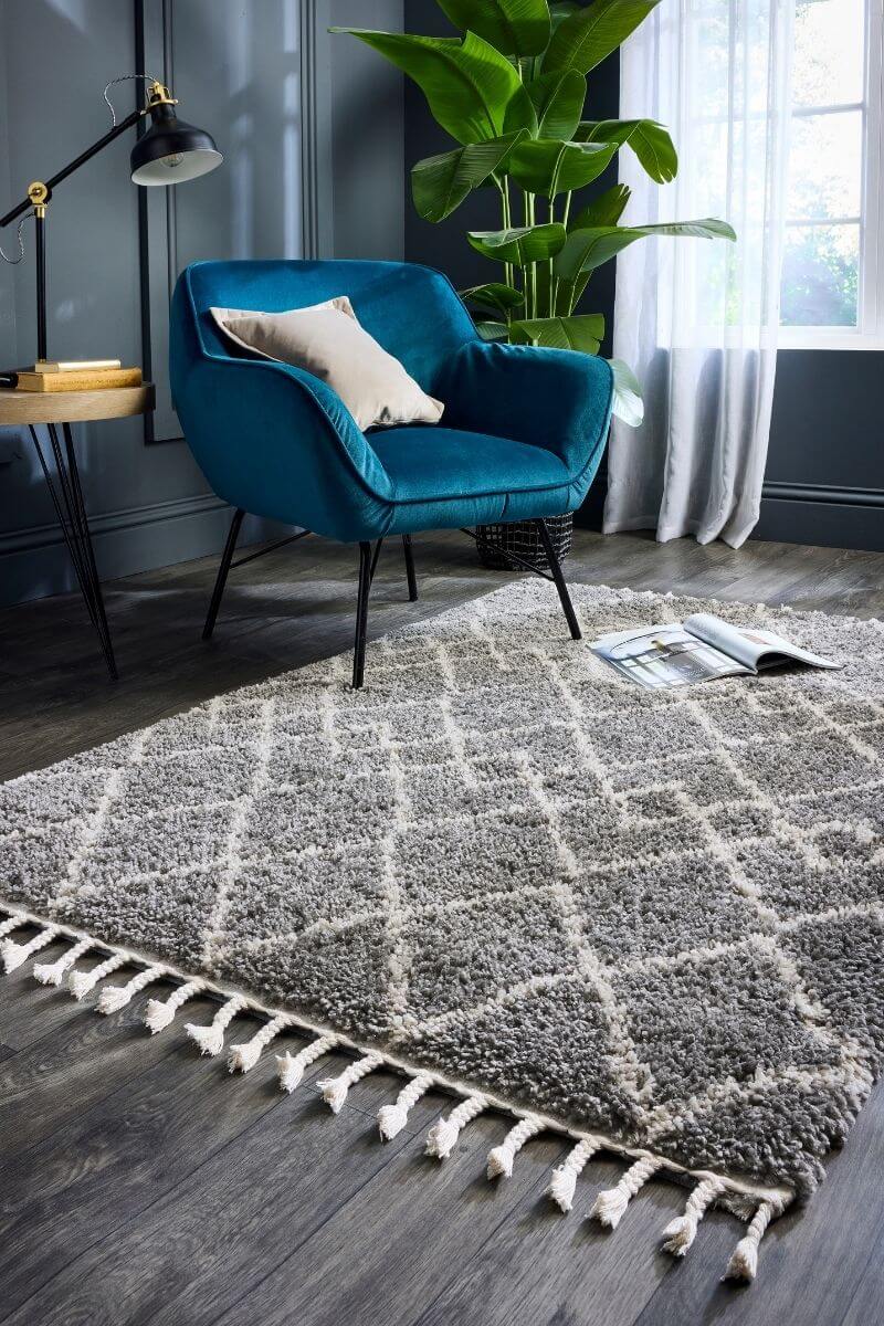 Moroccan-style shag rug in grey with white pattern, paired with a blue armchair in a stylish living room setting.