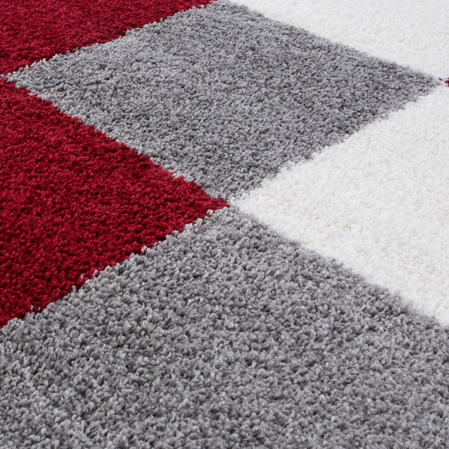 Close-up of a geometric-patterned rug with red, gray, and white squares.