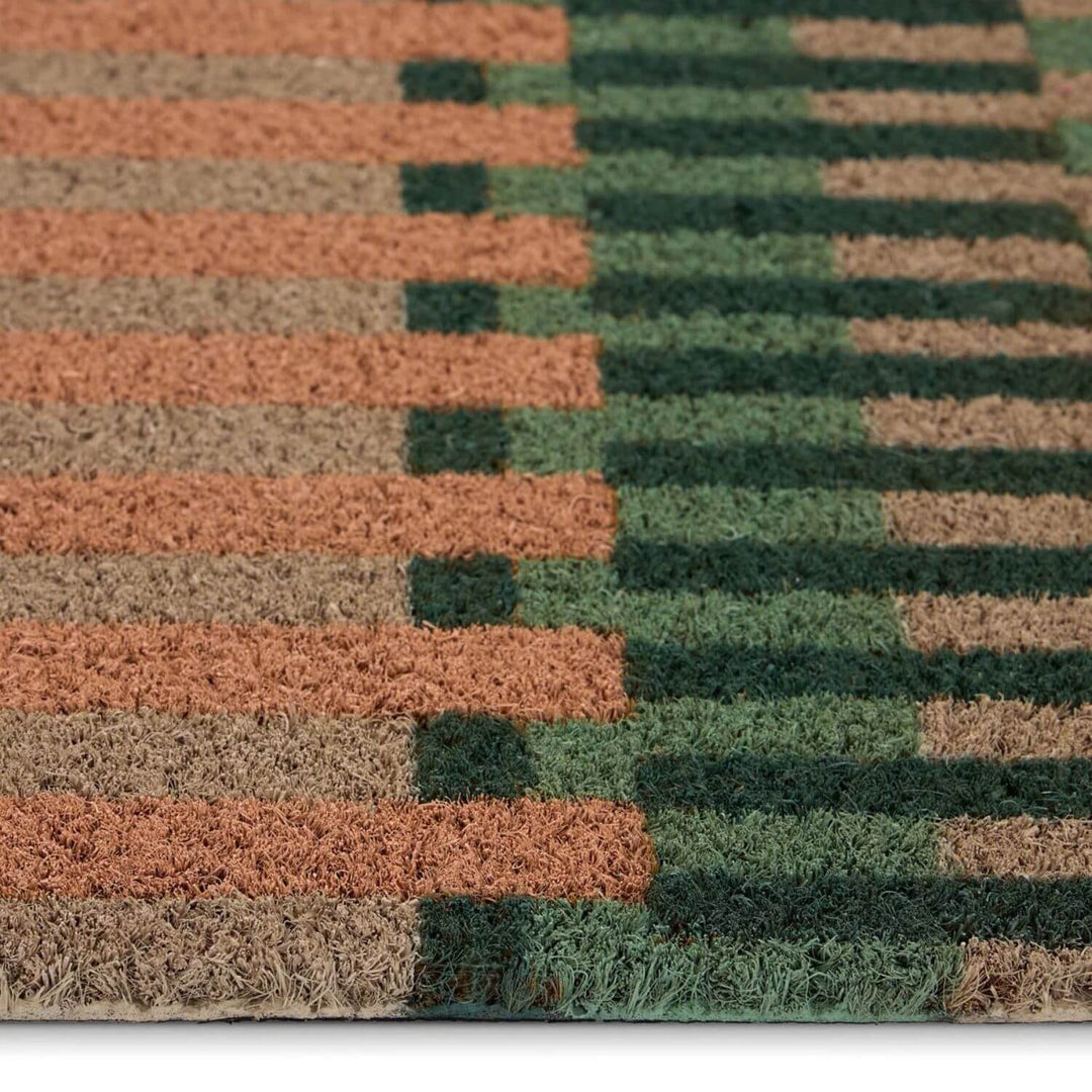 Close-up of a doormat with brown and green striped pattern