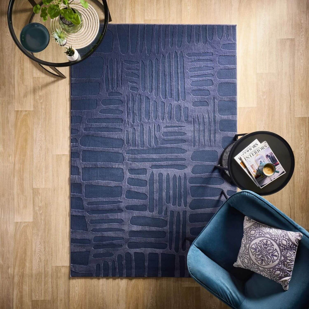 Blue patterned rug on a wooden floor with a blue chair and small table.