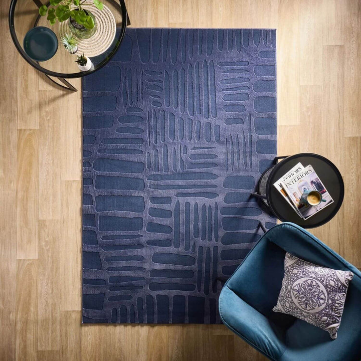 Blue patterned rug on a wooden floor with a blue chair and small table.