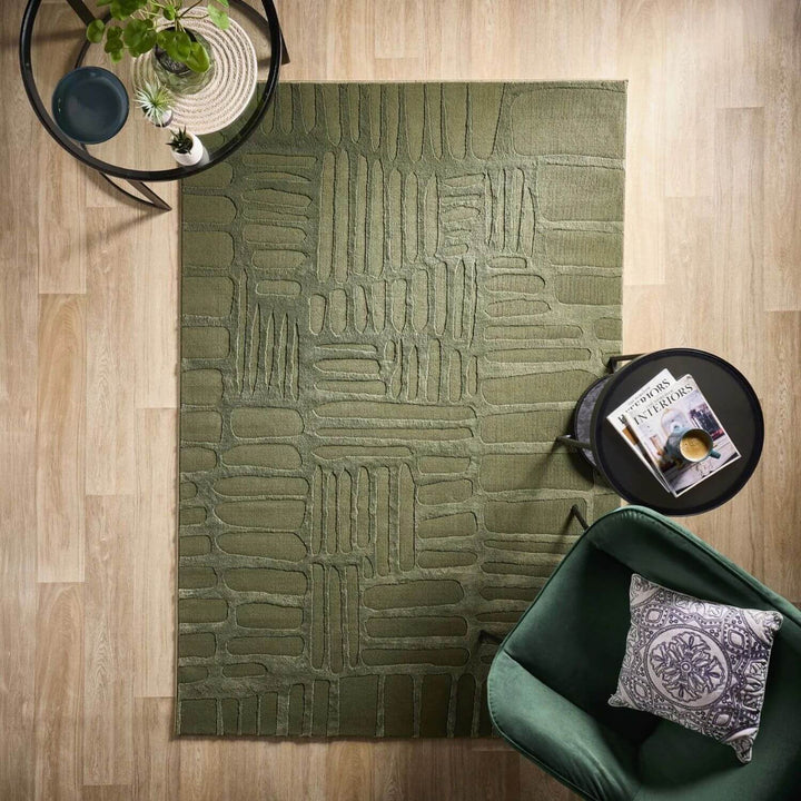 Green textured rug on a wooden floor with a green chair and small table.