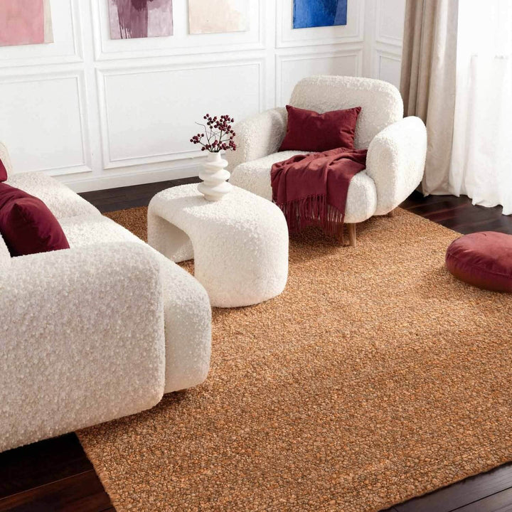 Modern living room with white armchairs, a brown rug, and decorative pillows.