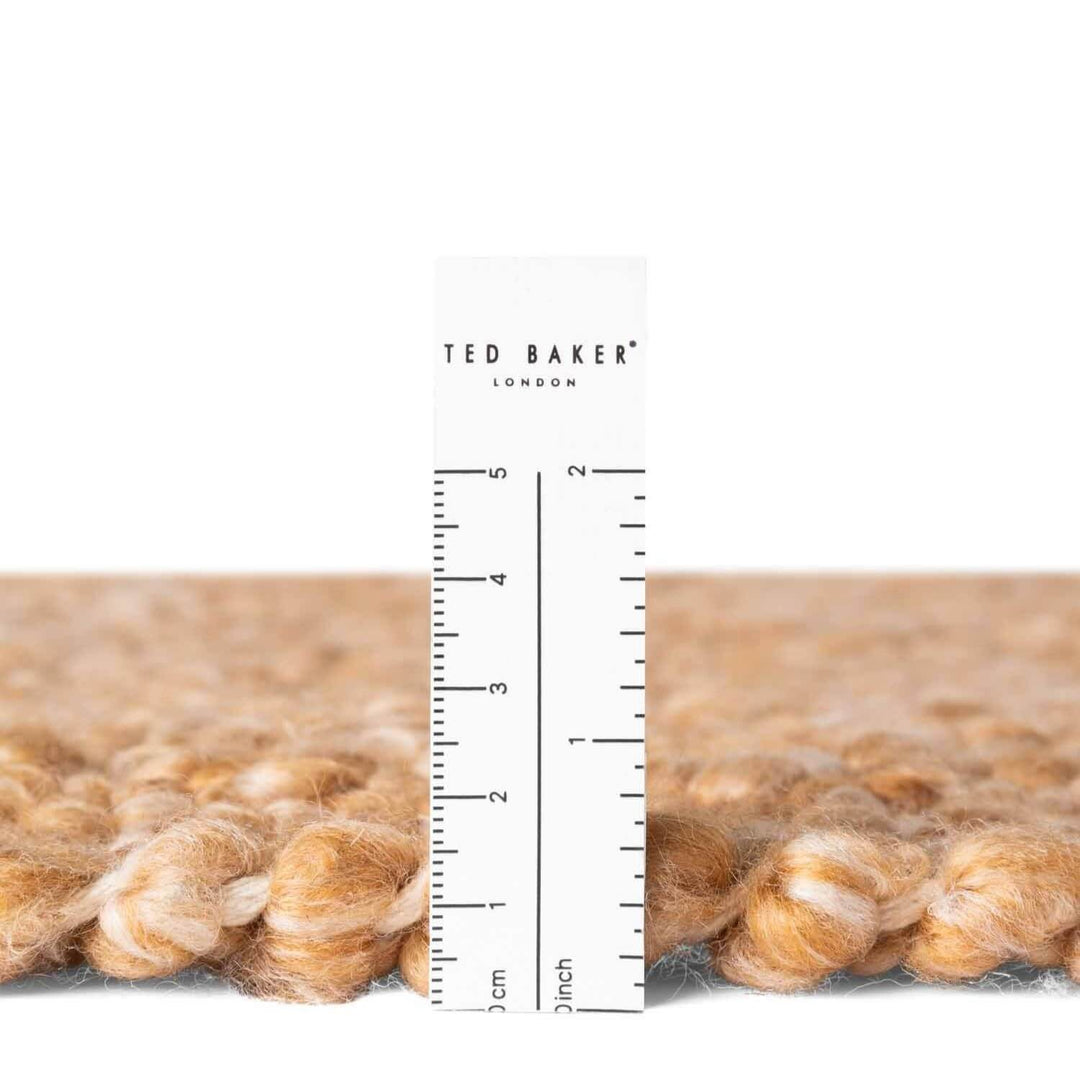 Close-up of a textured fabric with a ruler and 'Ted Baker' branding.