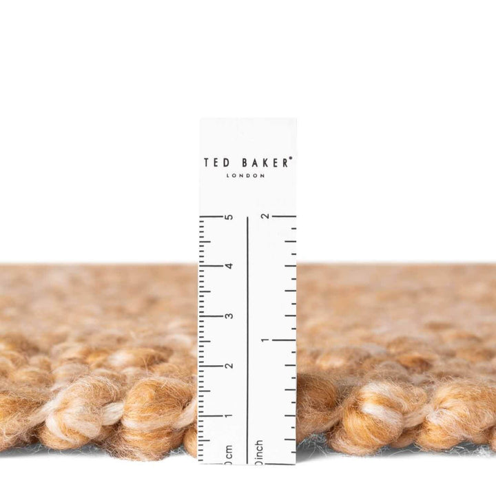 Close-up of a textured fabric with a ruler and 'Ted Baker' branding.