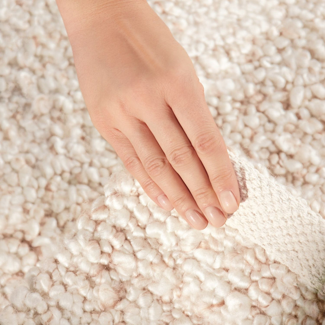 Hand touching a textured beige carpet