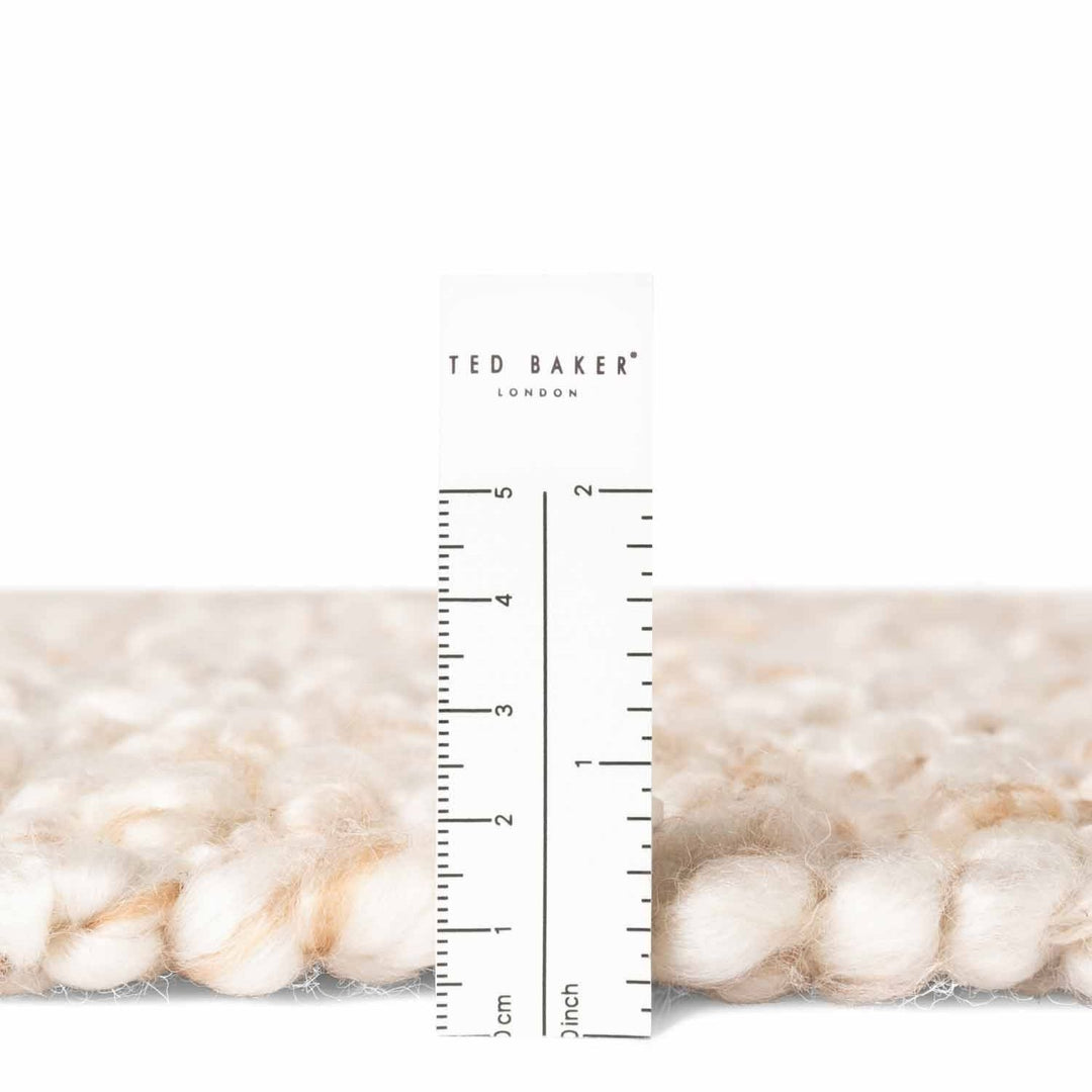 Close-up of textured fabric with a ruler and 'Ted Baker' branding.